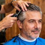 Homme d'âge mûr avec visage ovale portant une chemise bleue vive lors d'une coupe de cheveux chez le coiffeur